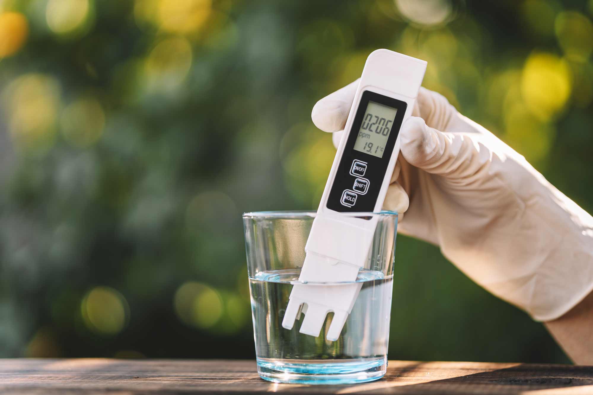 persona midiendo la dureza del agua con un dispositivo especial en un vaso de agua 